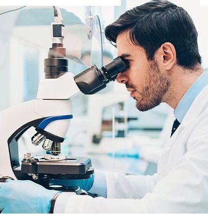 Lab technician examining a slide under a microscope